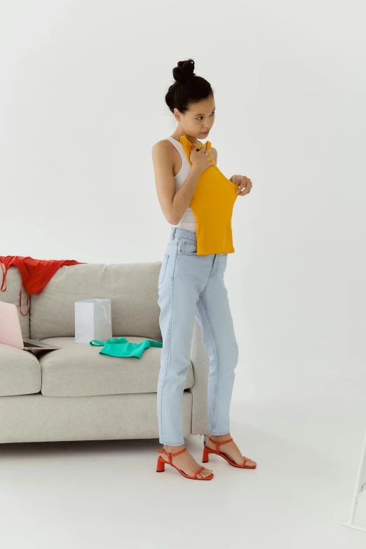 a girl standing by a couch holding up a banana