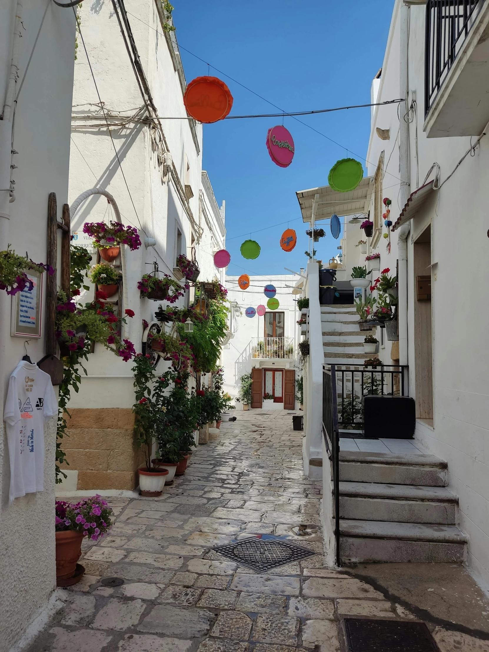 an alley way with some flowers and umbrellas