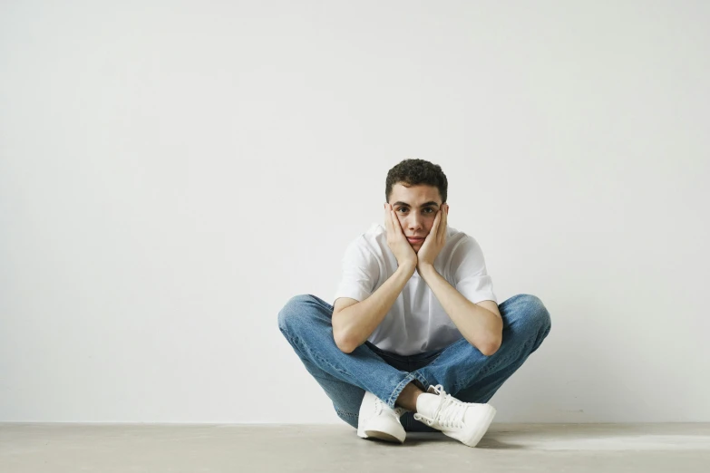 a young man sitting on the floor posing for the camera