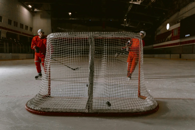 two men in orange outfits playing a game of ice hockey