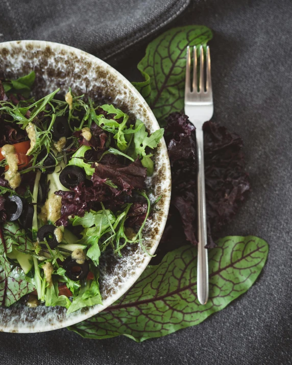 a white plate topped with salad next to silverware