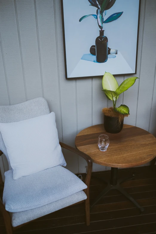 the small table with a glass and a vase sits on a wooden table near the painting