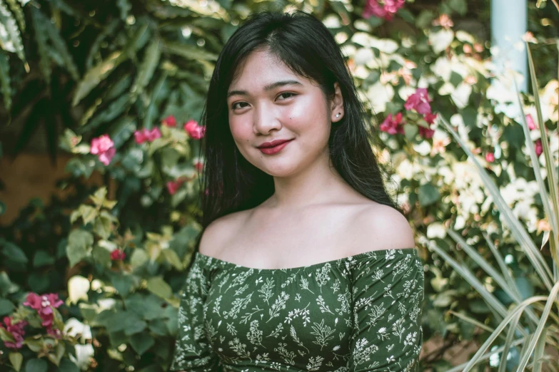 a young woman posing in front of a bush and shrubbery