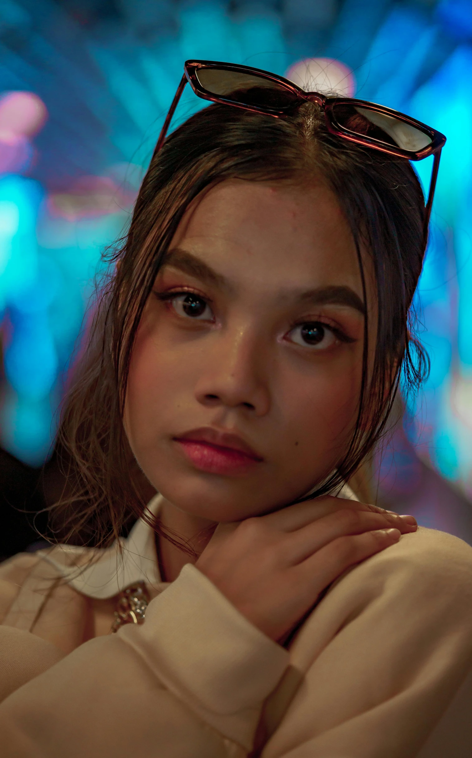 a young woman wearing sunglasses standing in front of colorful lights