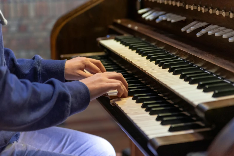 a man in blue sweater playing an organ with a white pipe