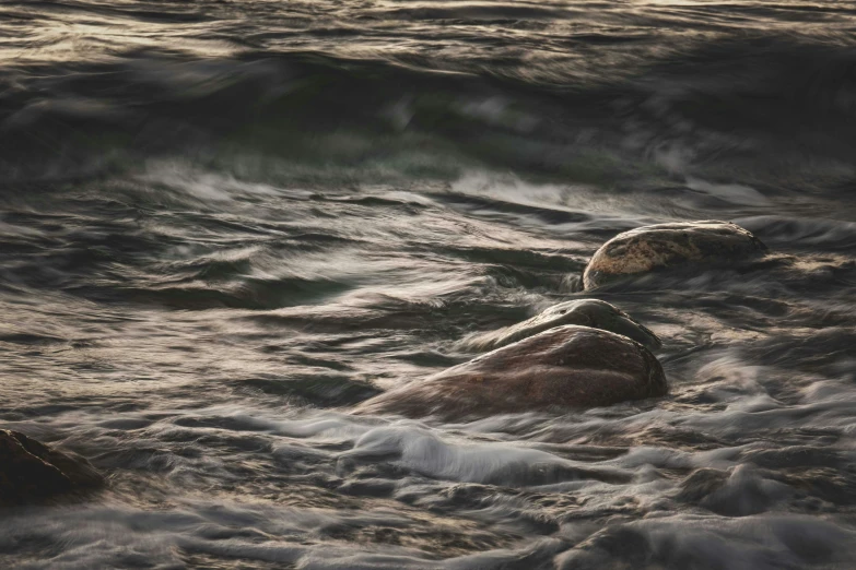 there are two rocks on the water near the shore