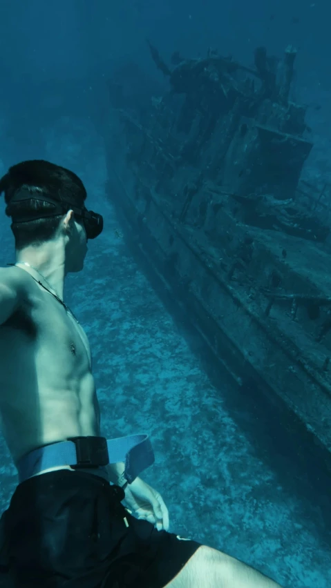 a man under water in front of a sunken ship