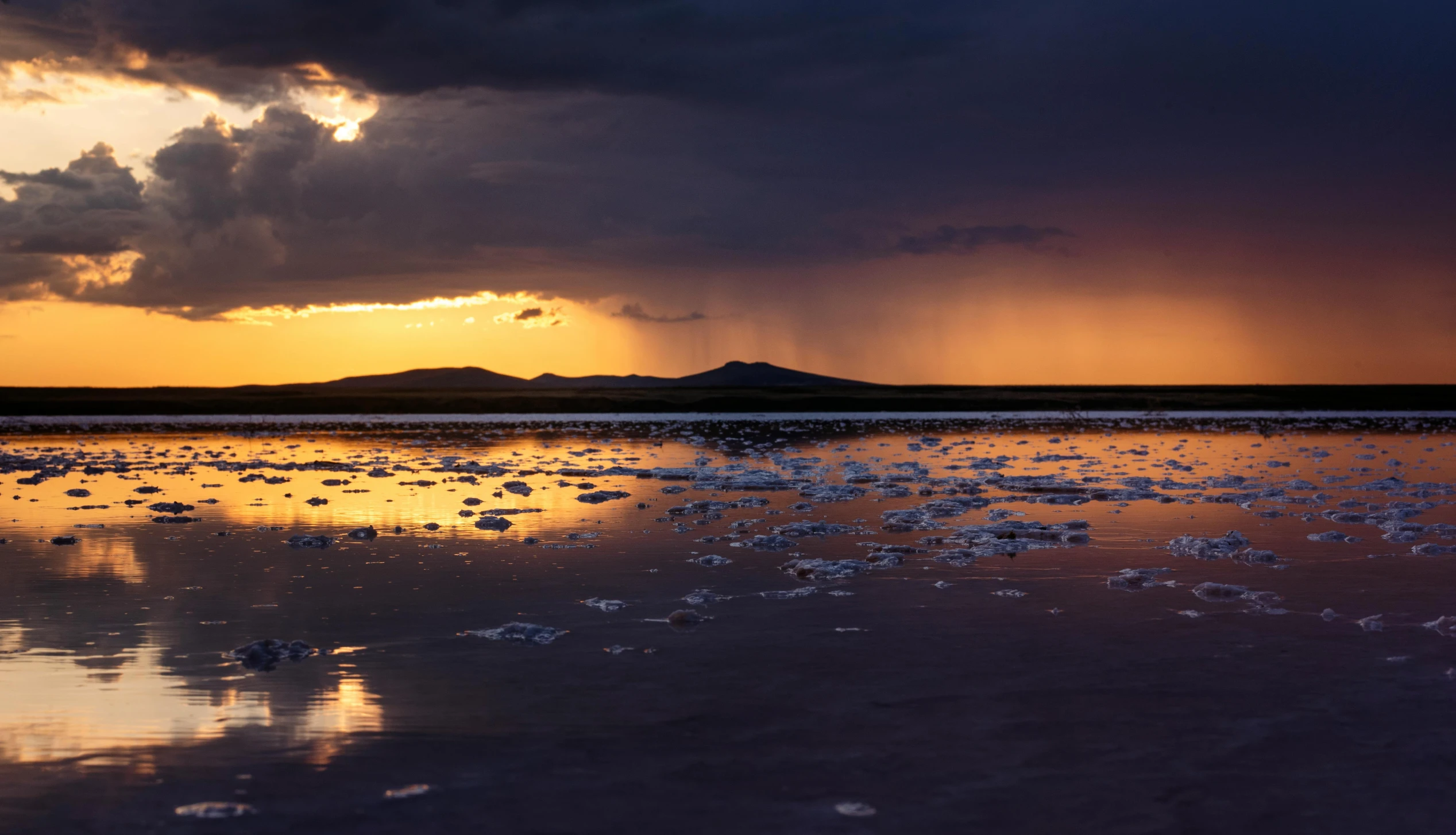 a sunset with rain coming in through clouds