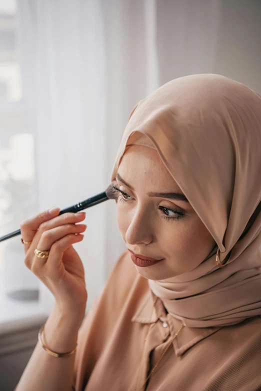 a woman with a veil on her head with a makeup brush
