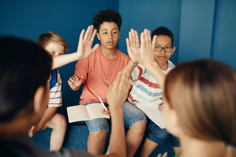 children are sitting on a couch with hands up to their parents