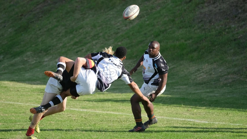 a man jumps and misses a ball as another tries to block him