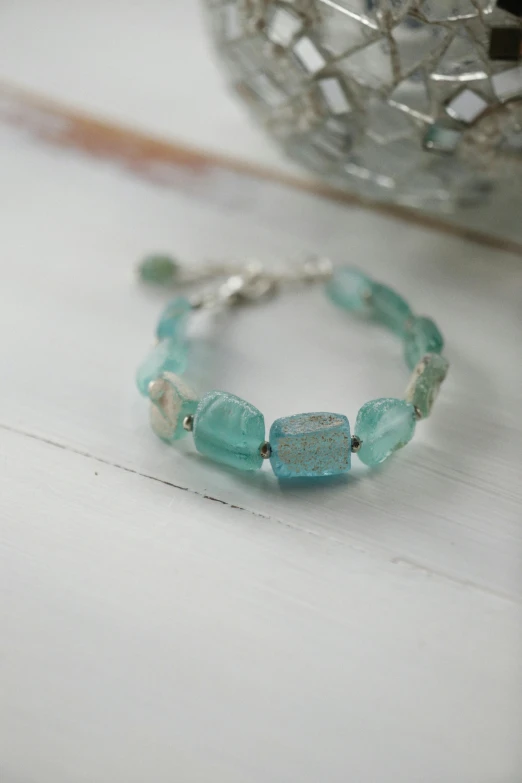 green beaded celet sitting on a table next to a small bowl