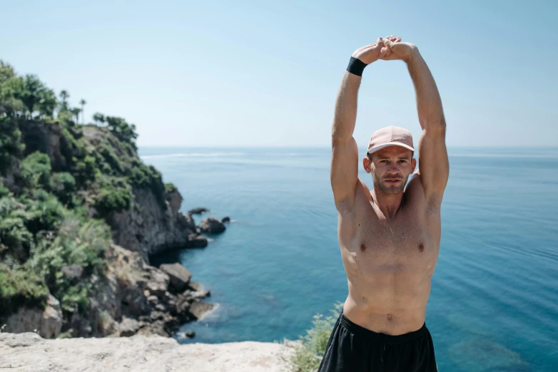 man standing on the edge of a cliff holding up his hands