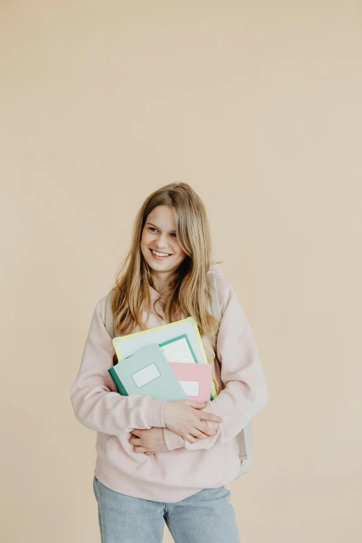 girl in pink sweatshirt holding an assortment of books