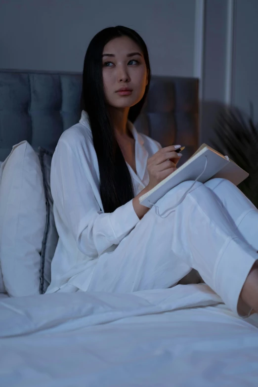 a woman sitting on the bed reading a book