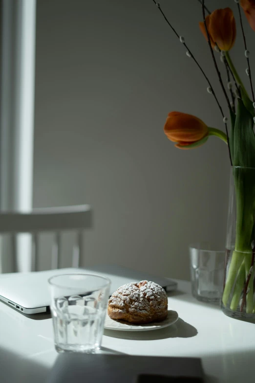 a table with a flower and glass vase next to it