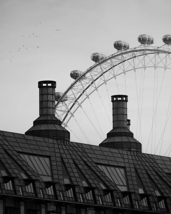 black and white pograph of an old building with a ferris wheel in the background