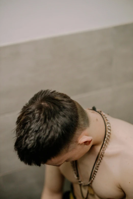 shirtless man taking a shower wearing chains and choker