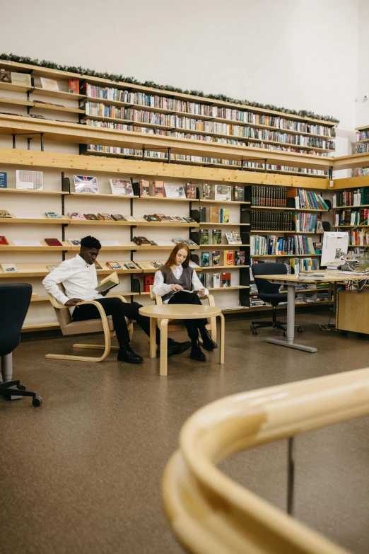 two people are sitting on chairs in front of bookshelves