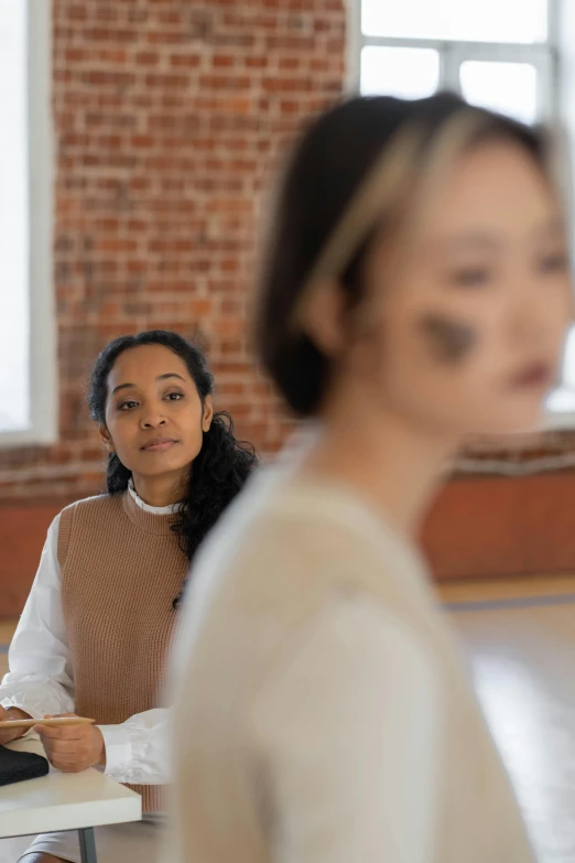 two women stand at the front of a room with brick walls