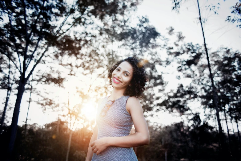 a woman is standing in the grass with trees