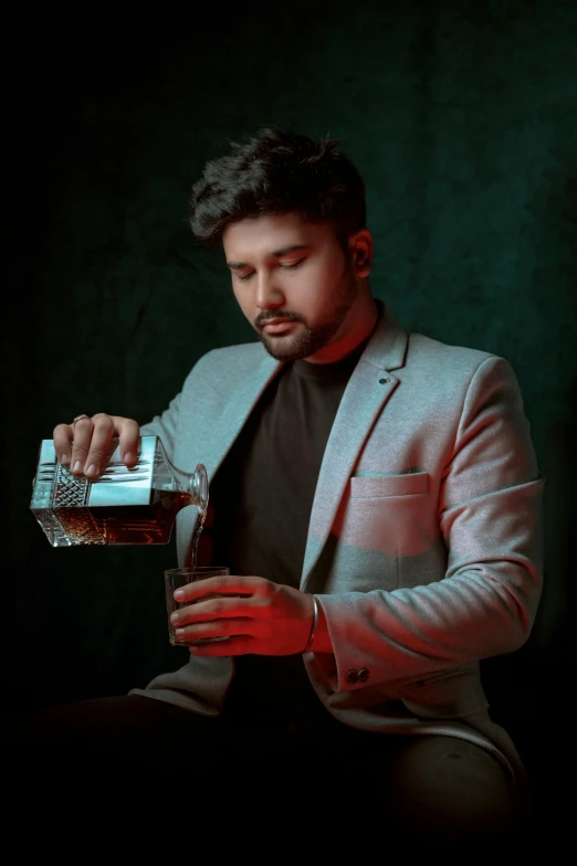 a man in a suit and tie sitting and holding a drink