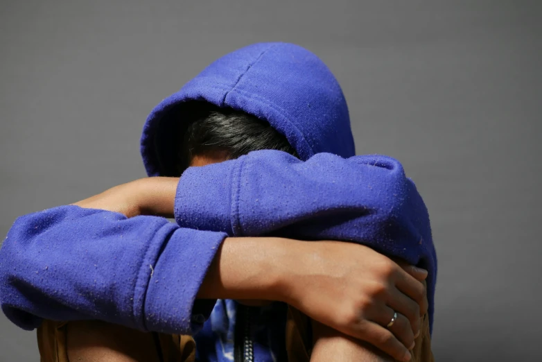 a woman in a purple sweater has her hands on her face