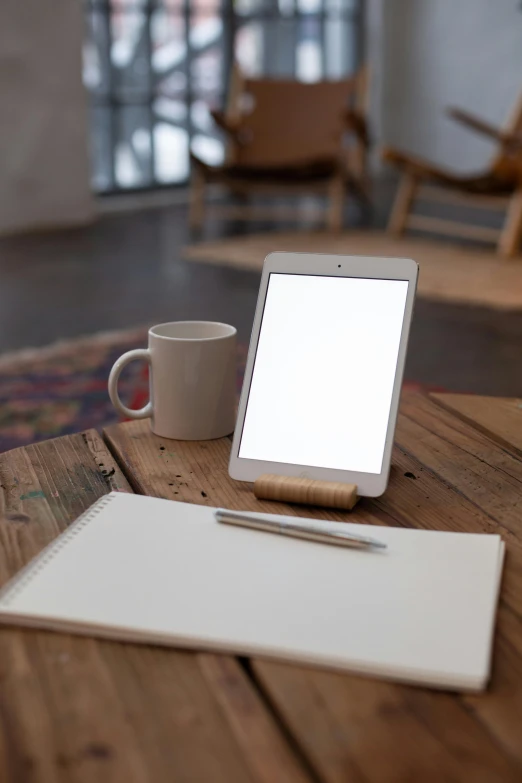 a table with a tablet a pen and coffee cup