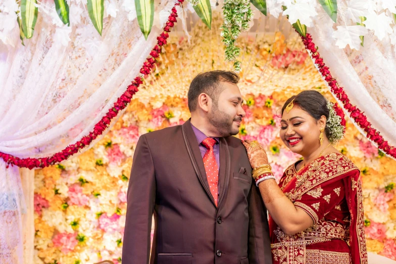 a bride and groom smile under a decorated arch