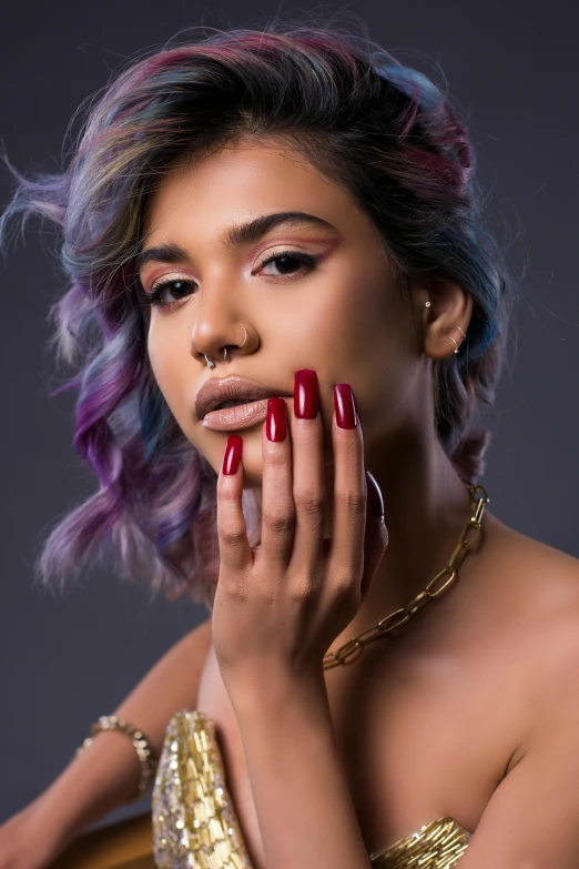 a woman with purple hair wearing gold and red nails