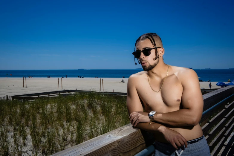 man standing with arms crossed next to the beach