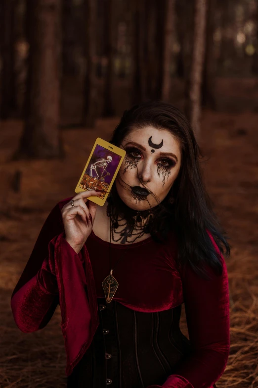 a woman with makeup and body paint holding up a card