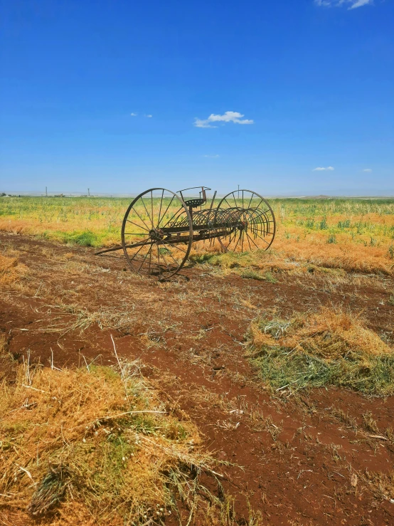 an old farm implements laying on top of a dry grass field