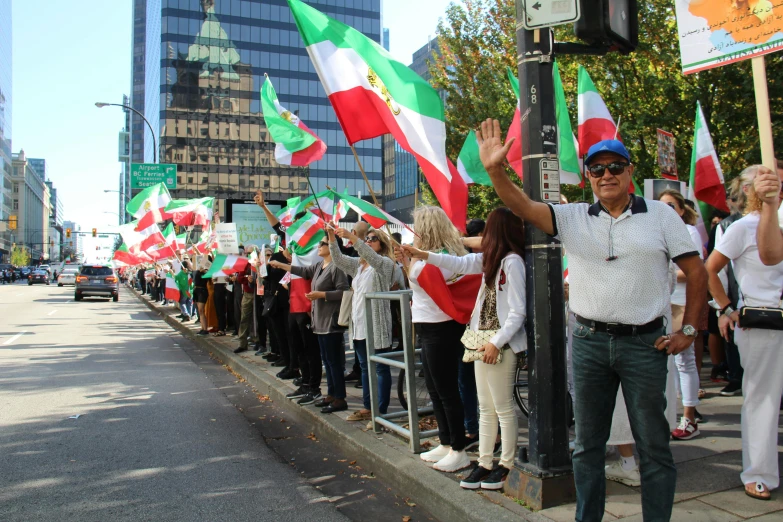 a group of people standing on the sidewalk holding flags