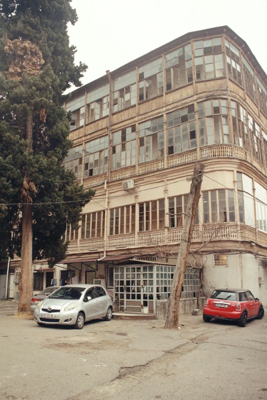 a building with lots of windows, cars and trees