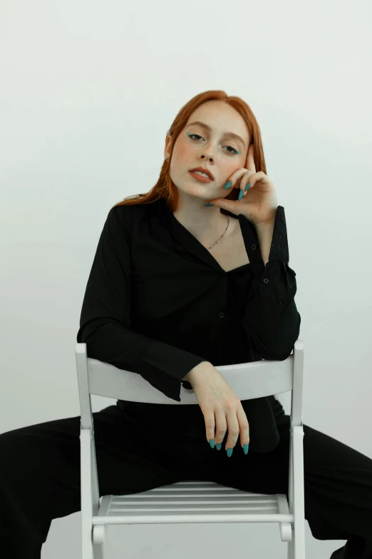 a redheaded woman sitting in a chair with her hand on her face