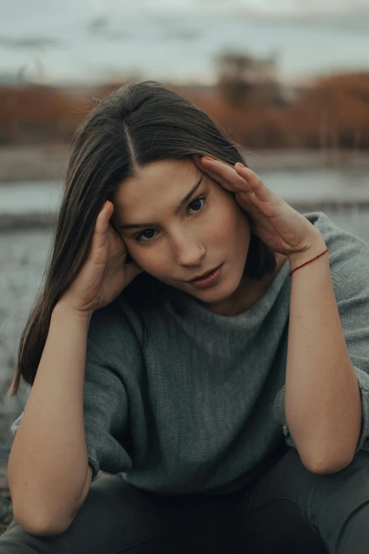 a woman is sitting in front of a body of water