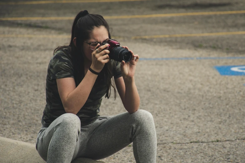woman squatting and taking pictures in pavement