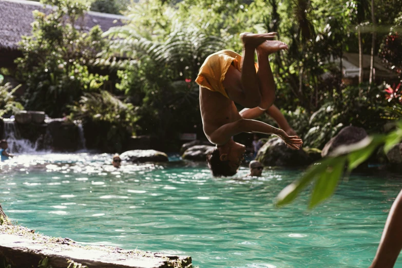 a person doing an acrobatic trick in front of water