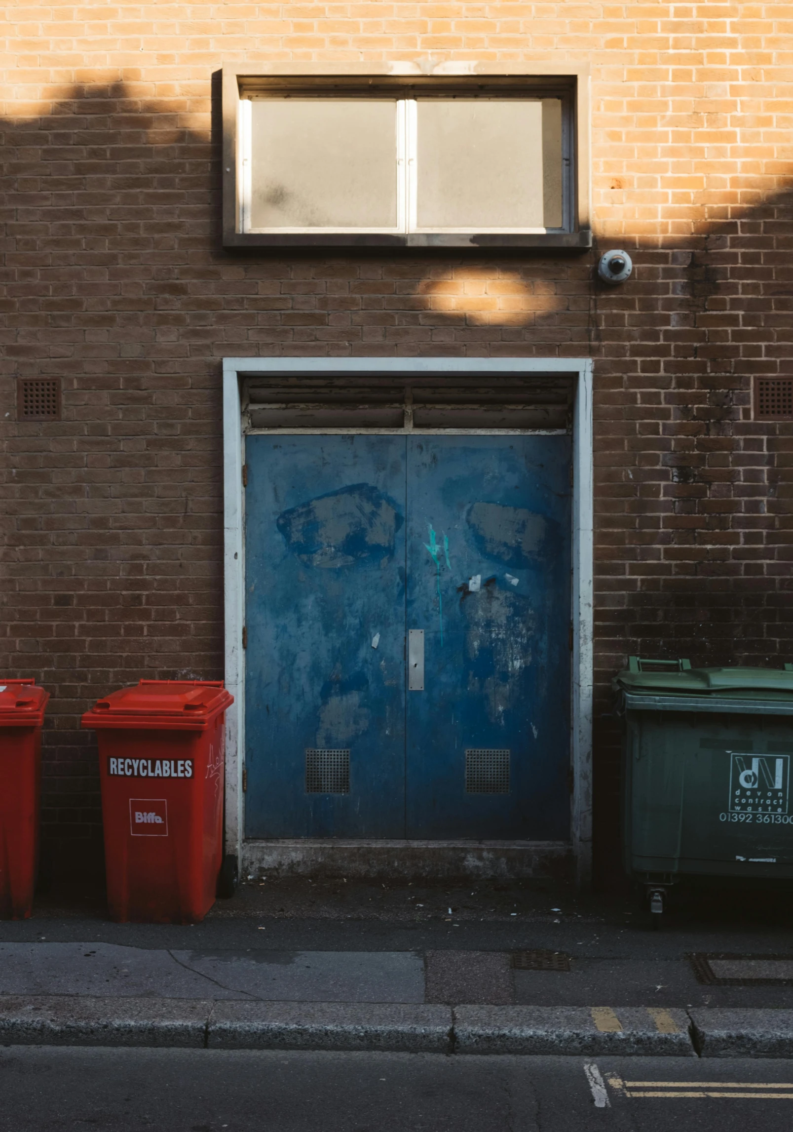 a building with three trash cans on the sidewalk outside