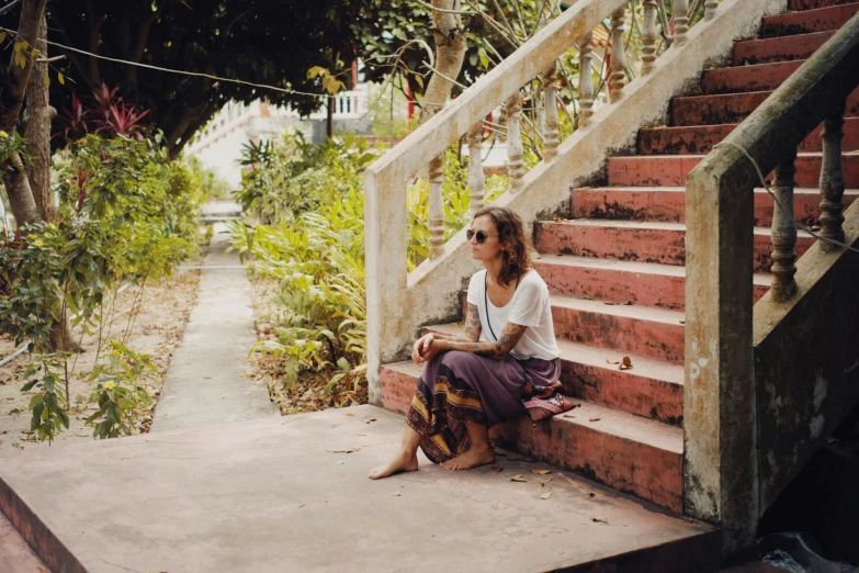 a woman sitting on the steps looking out to the garden