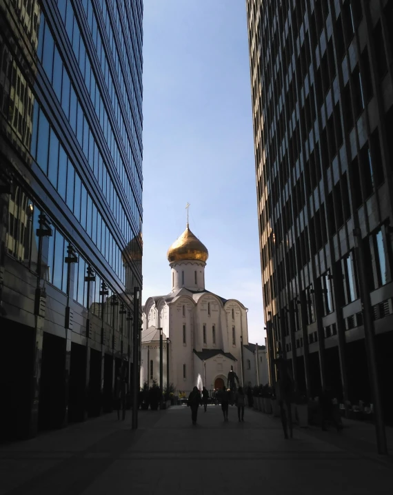 the building is white with a golden roof and two people walking by