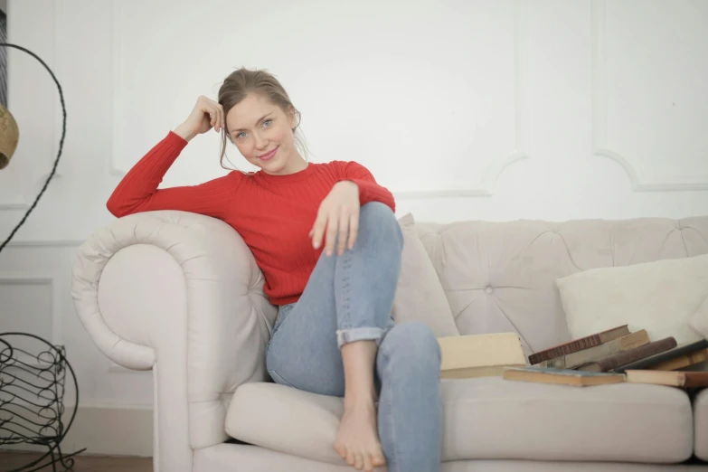 a woman sitting on top of a white couch with her legs crossed