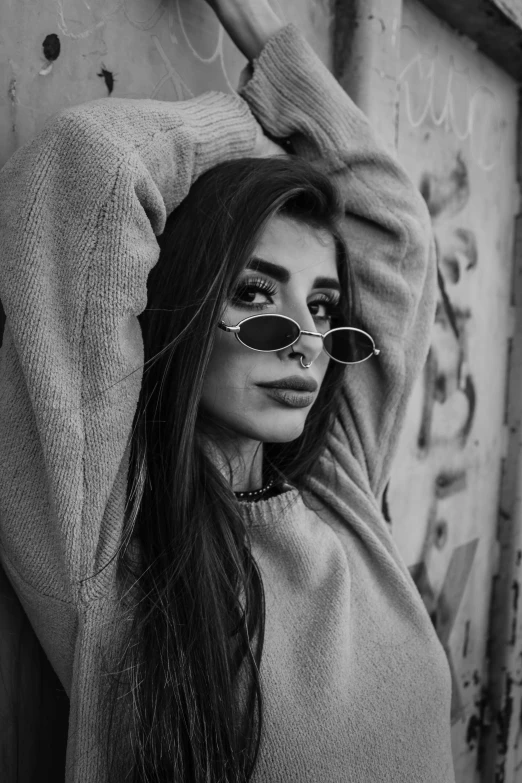 a beautiful young woman in sunglasses posing for a black and white po