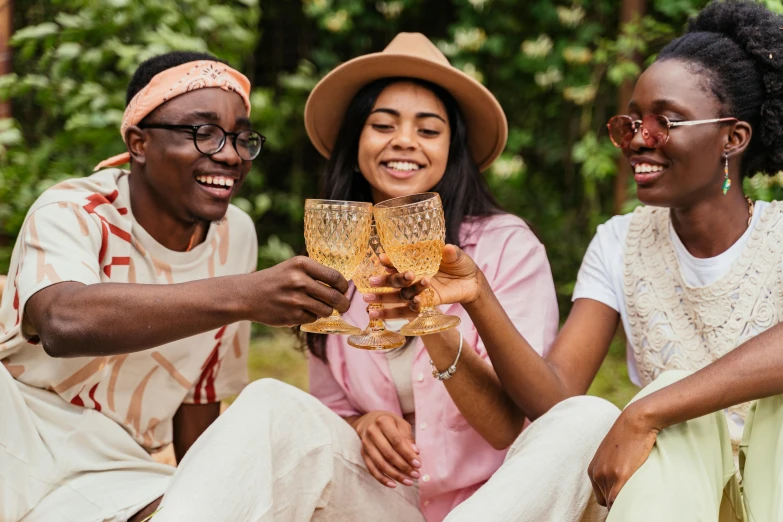 two women and a man hold wine glasses together