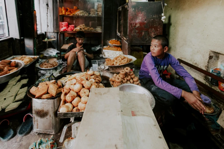 a man sitting on the floor next to a table full of food