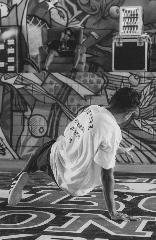 skateboarder leaning forward with his board near wall with graffiti