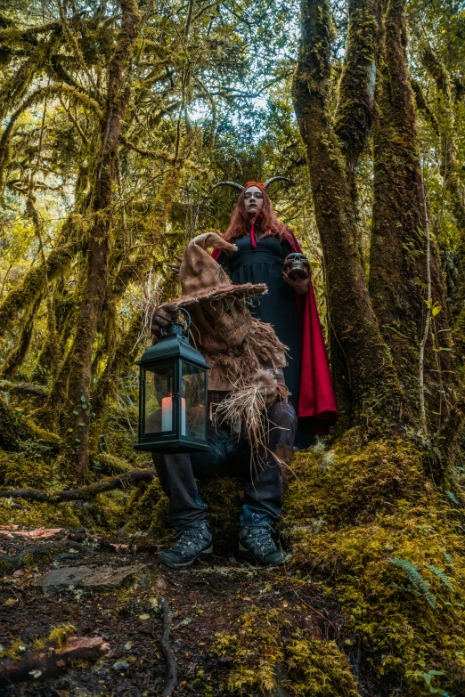 a man dressed up in costume is holding a lantern in the forest