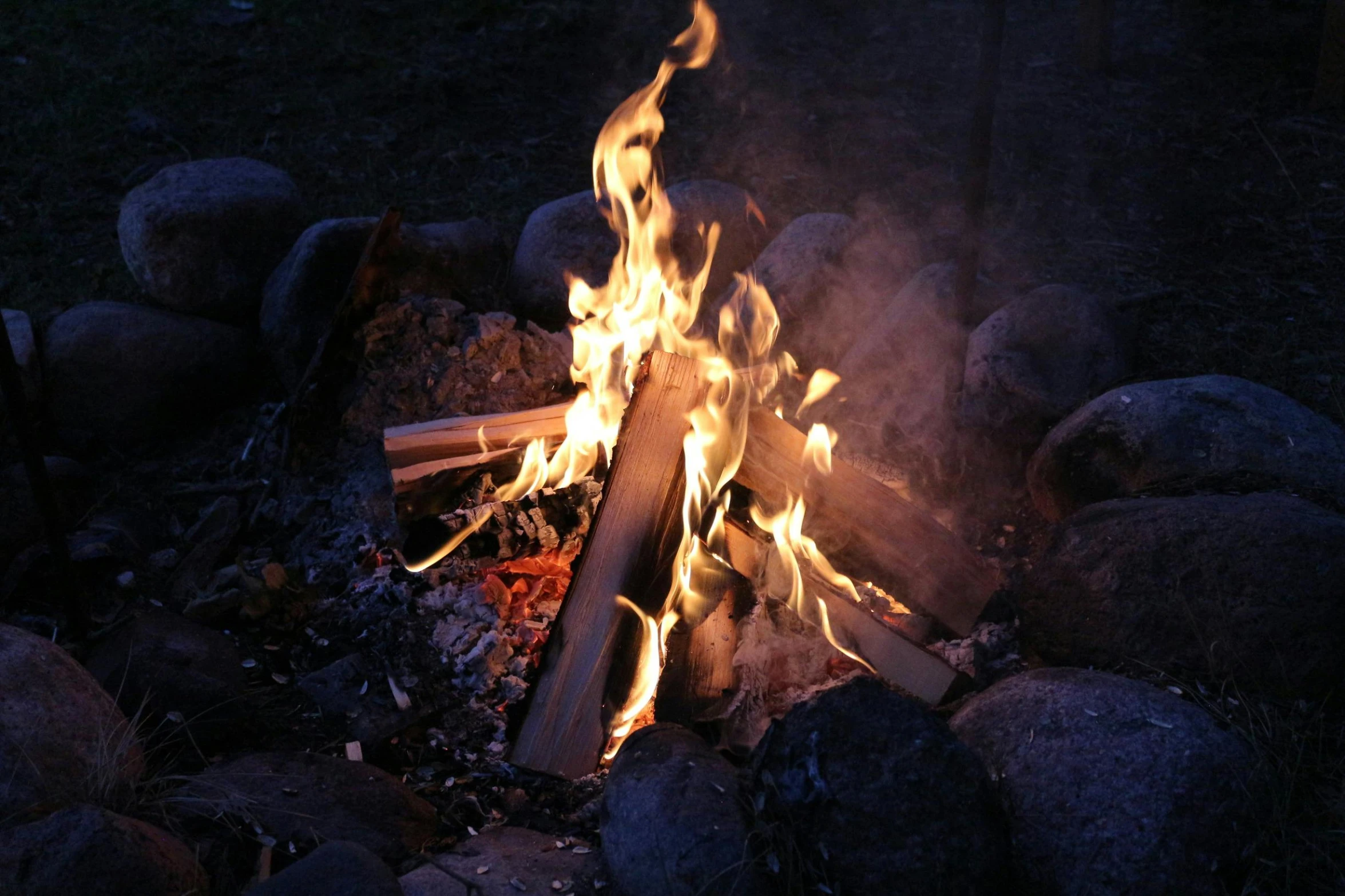 a fire burns near some rocks on the ground