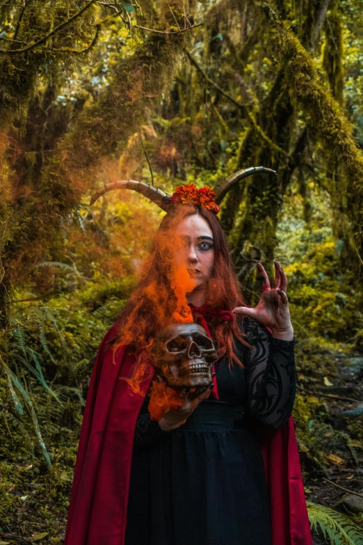 a woman with long red hair wearing a horned mask and a black dress